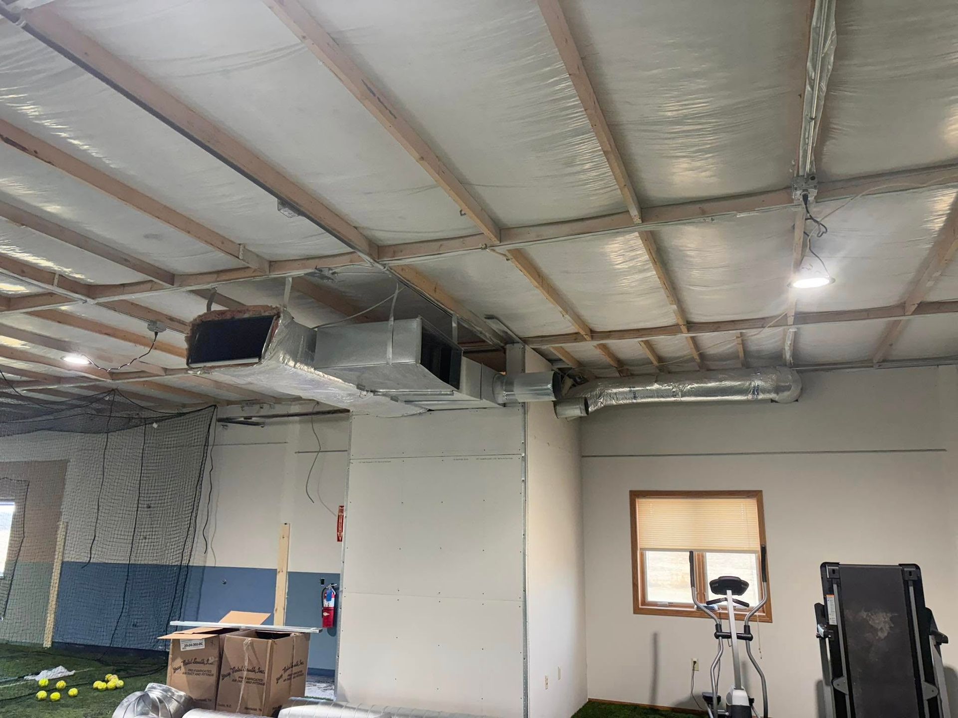 Lake Area Heating and Cooling LLC | A room with boxes on the floor and a treadmill in it.