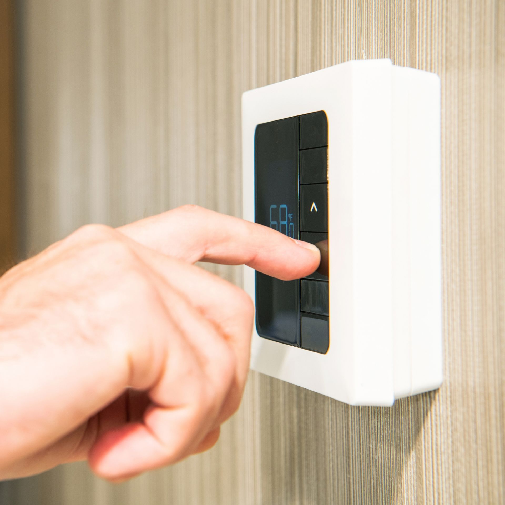 Lake Area Heating and Cooling LLC | A person is pressing a button on a thermostat.