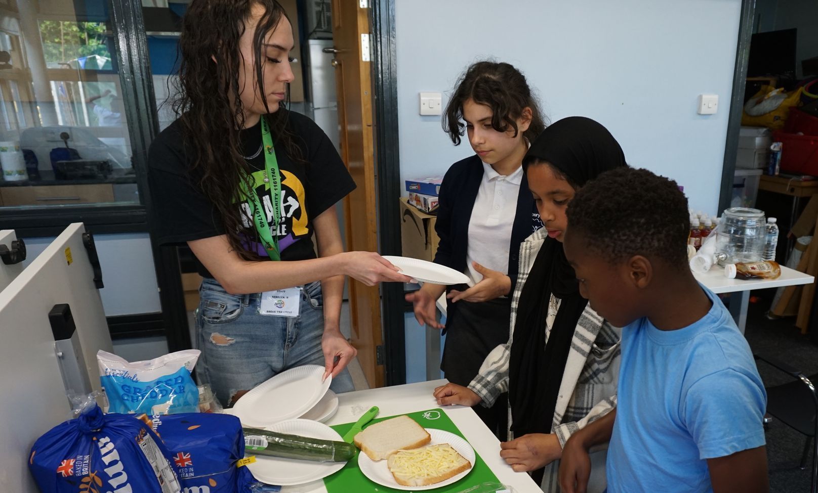 A group of children are standing around a table with plates of food.