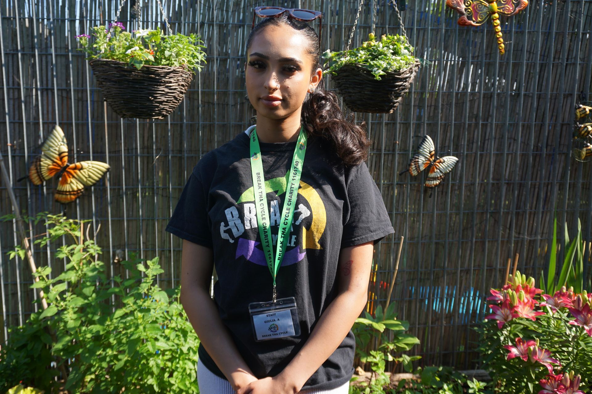 A woman in a black shirt is standing in front of a fence.