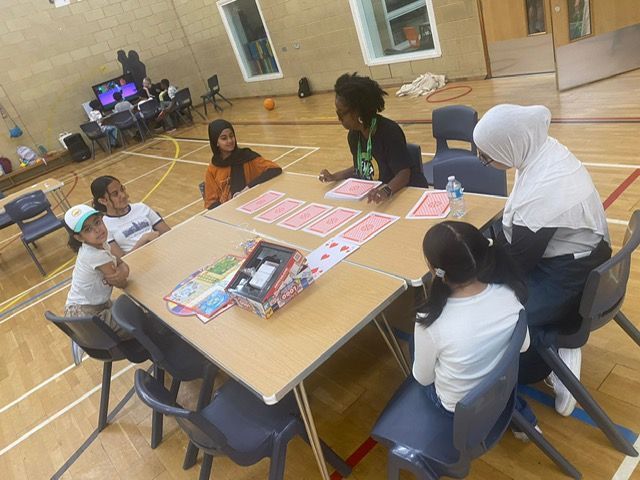 A group of children are sitting around a table with cards on it.