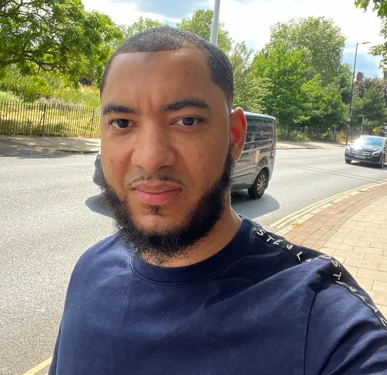 A man with a beard is taking a selfie on the side of the road