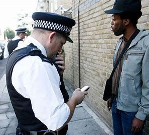 A police officer is talking to a man while looking at his cell phone.