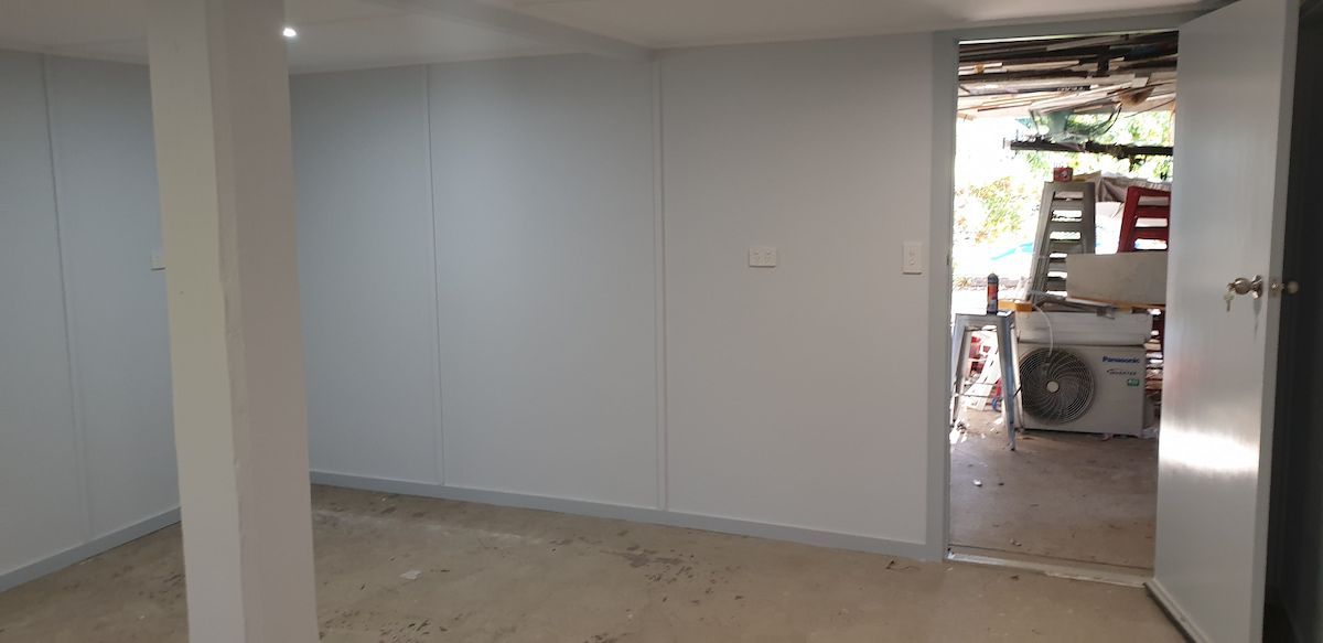 An Empty Room With White Walls and a Door Leading to a Garage — Gaspen Builders & Carpenters in Kirwan, QLD