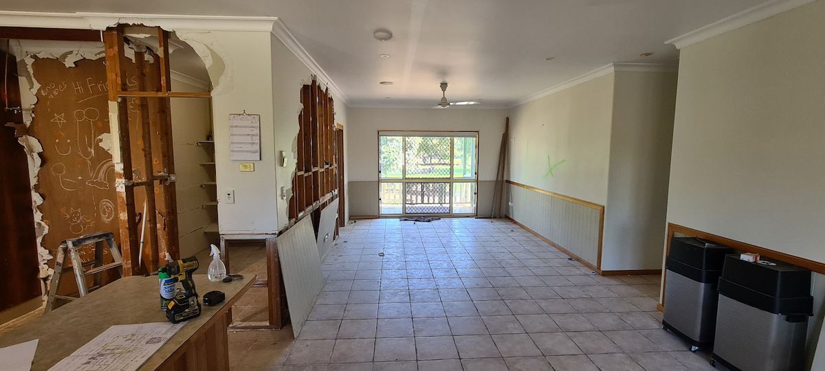 A Large Empty Room With a Tiled Floor and a Window — Gaspen Builders & Carpenters in Kirwan, QLD