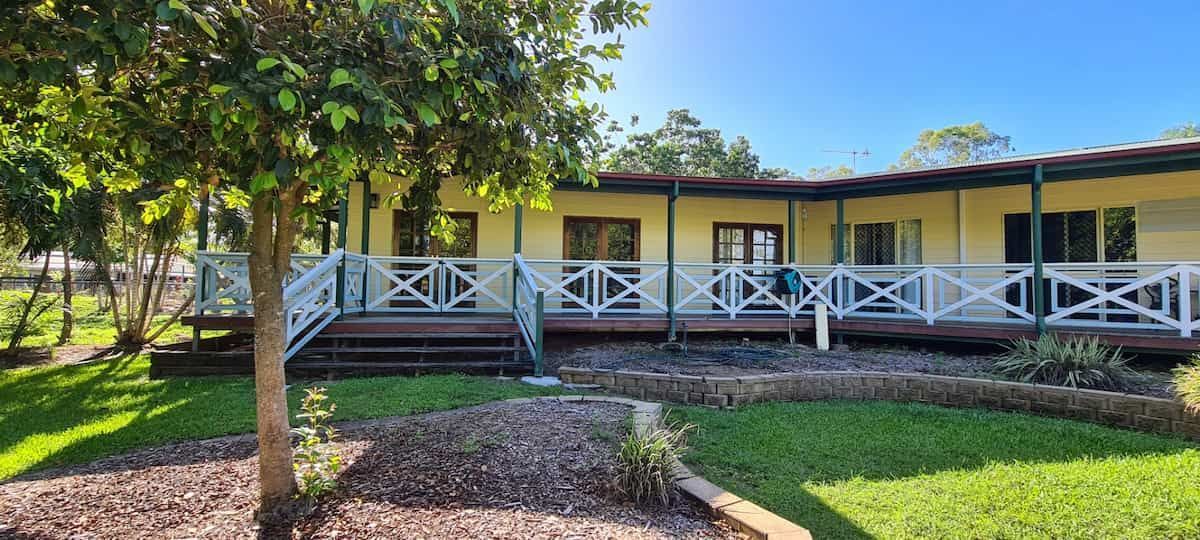 A Large House With a Large Porch and a Tree in Front of It — Gaspen Builders & Carpenters in Kirwan, QLD