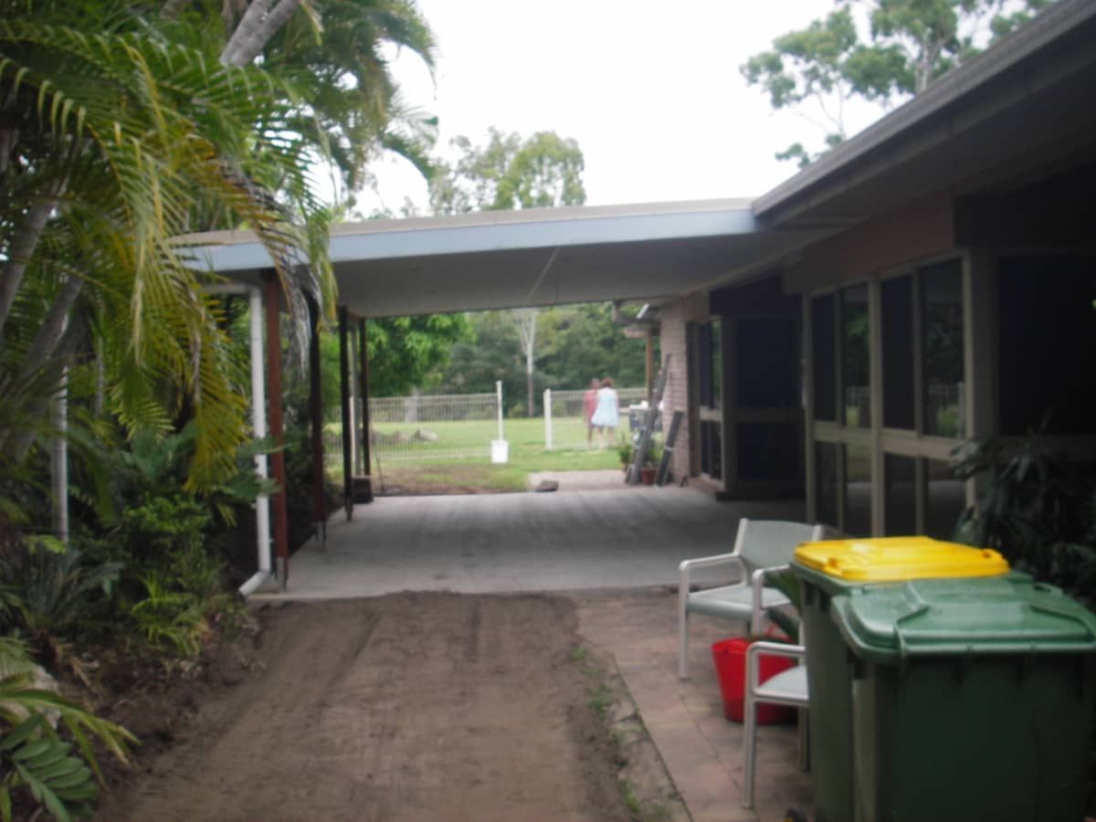 A Green Trash Can Sits in Front of a House — Gaspen Builders & Carpenters in Kirwan, QLD