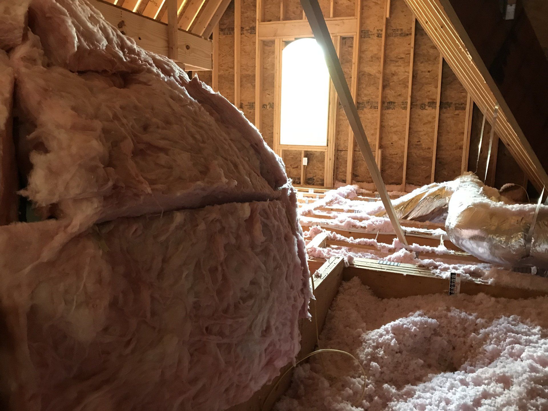 An attic with a lot of insulation and a window