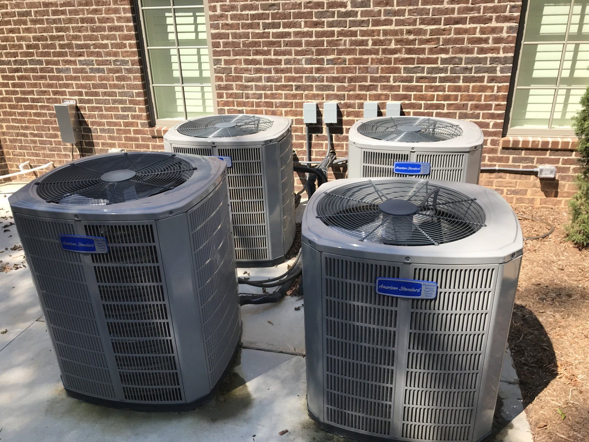 Three air conditioners are sitting outside of a brick building