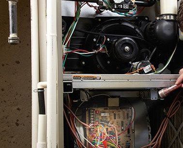 A person is working on a heater with a lot of wires coming out of it