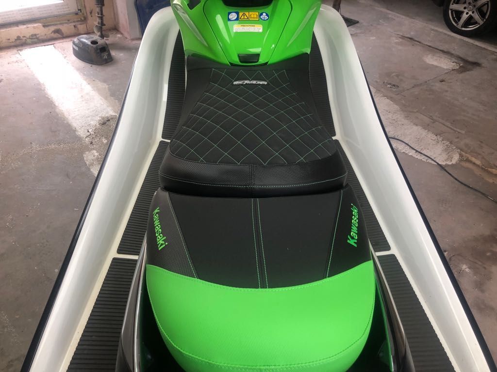 A green and black jet ski is parked in a garage.