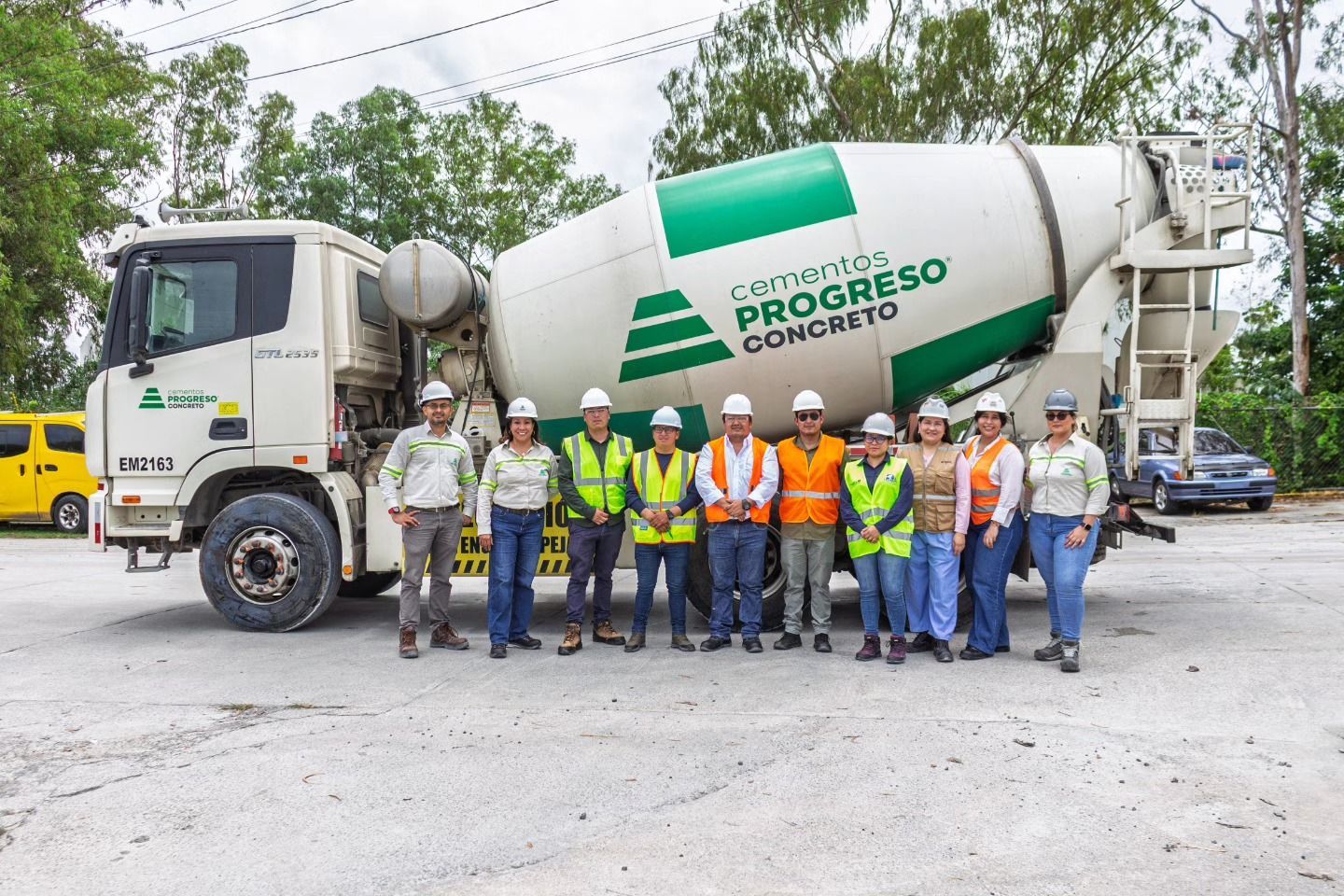 Grupo de personas posando frente a un camión hormigonera. El camión es blanco y verde. Parecen estar trabajando.
