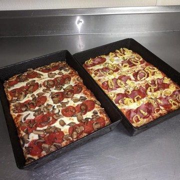 Two rectangular pizzas in baking pans: one with pepperoni and mushrooms, the other with pepperoni and mustard.