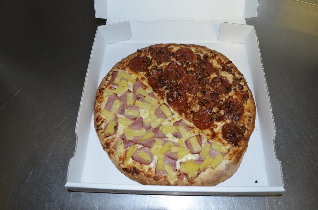 Pizza in box, half pepperoni, half pineapple and ham.
