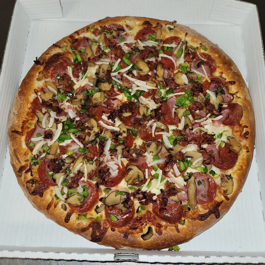 Pizza with pepperoni, mushrooms, peppers, and cheese in a cardboard box.