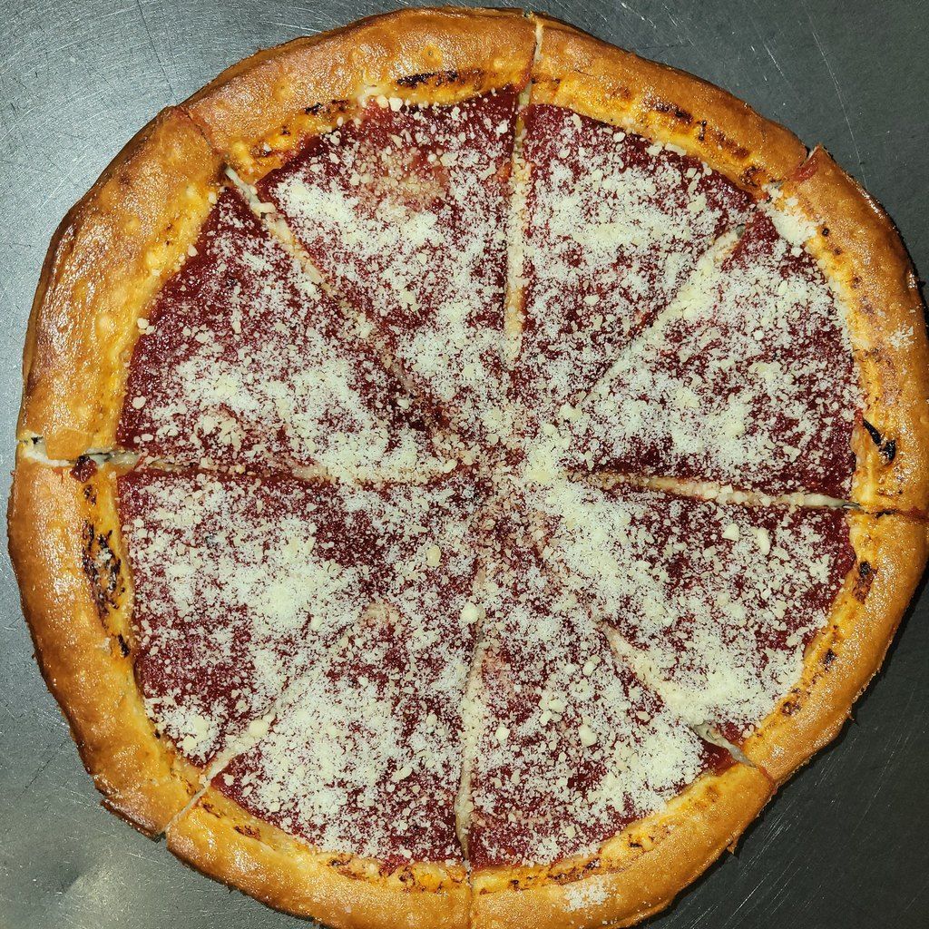 Deep-dish pizza, sliced into wedges, with red sauce and sprinkled cheese on a metallic surface.