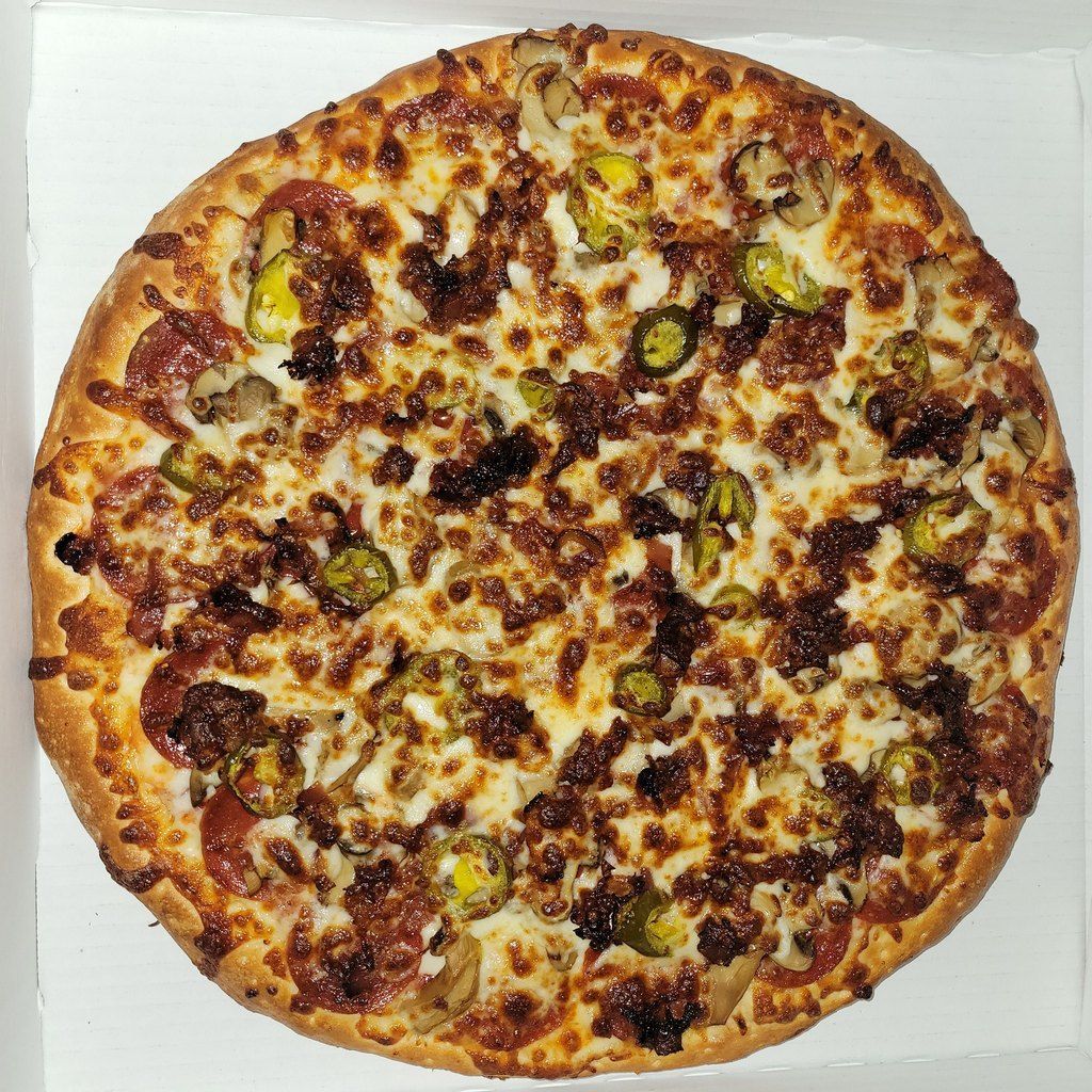 Pizza with pepperoni, peppers, mushrooms, and cheese in a box.