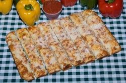 Breadsticks with cheese, peppers, and dipping sauce on a checkered tablecloth.