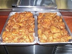 Two aluminum trays filled with golden-brown fried chicken.