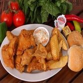 Plate of fried chicken wings, fries, coleslaw, rolls, tomatoes, peppers, and condiments.