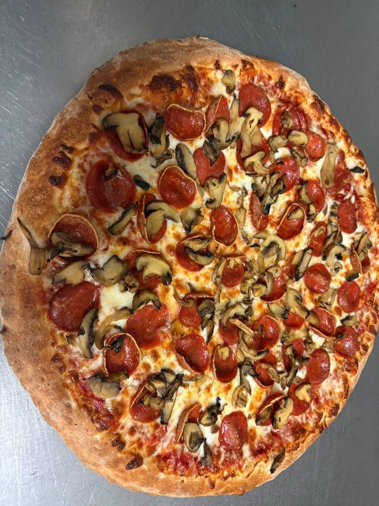 Pepperoni and mushroom pizza on a metal surface.