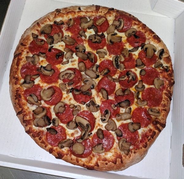 Pizza with pepperoni and mushrooms in a white box.