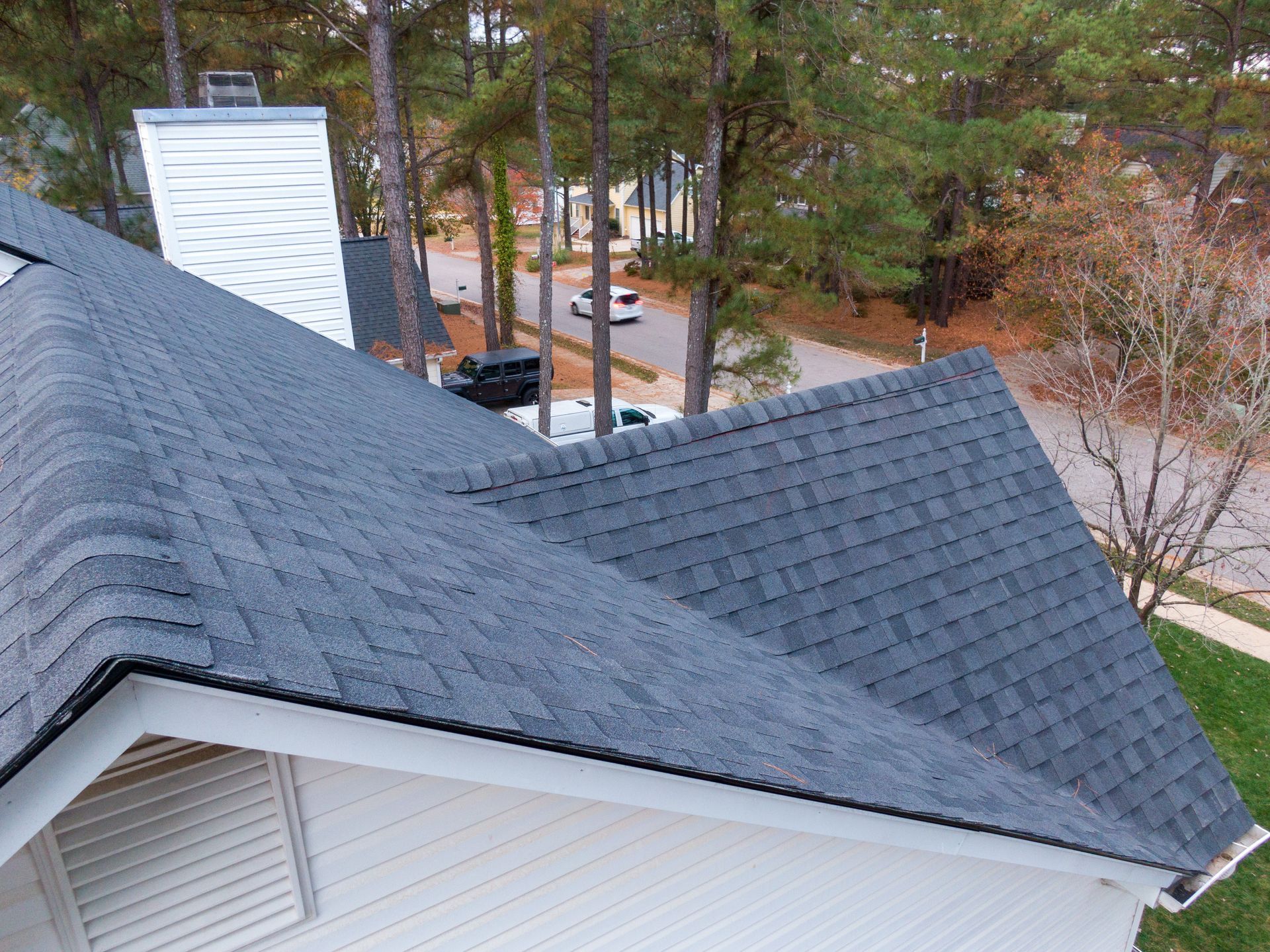 Close-up view of a house roof with new asphalt shingles and eave detail.