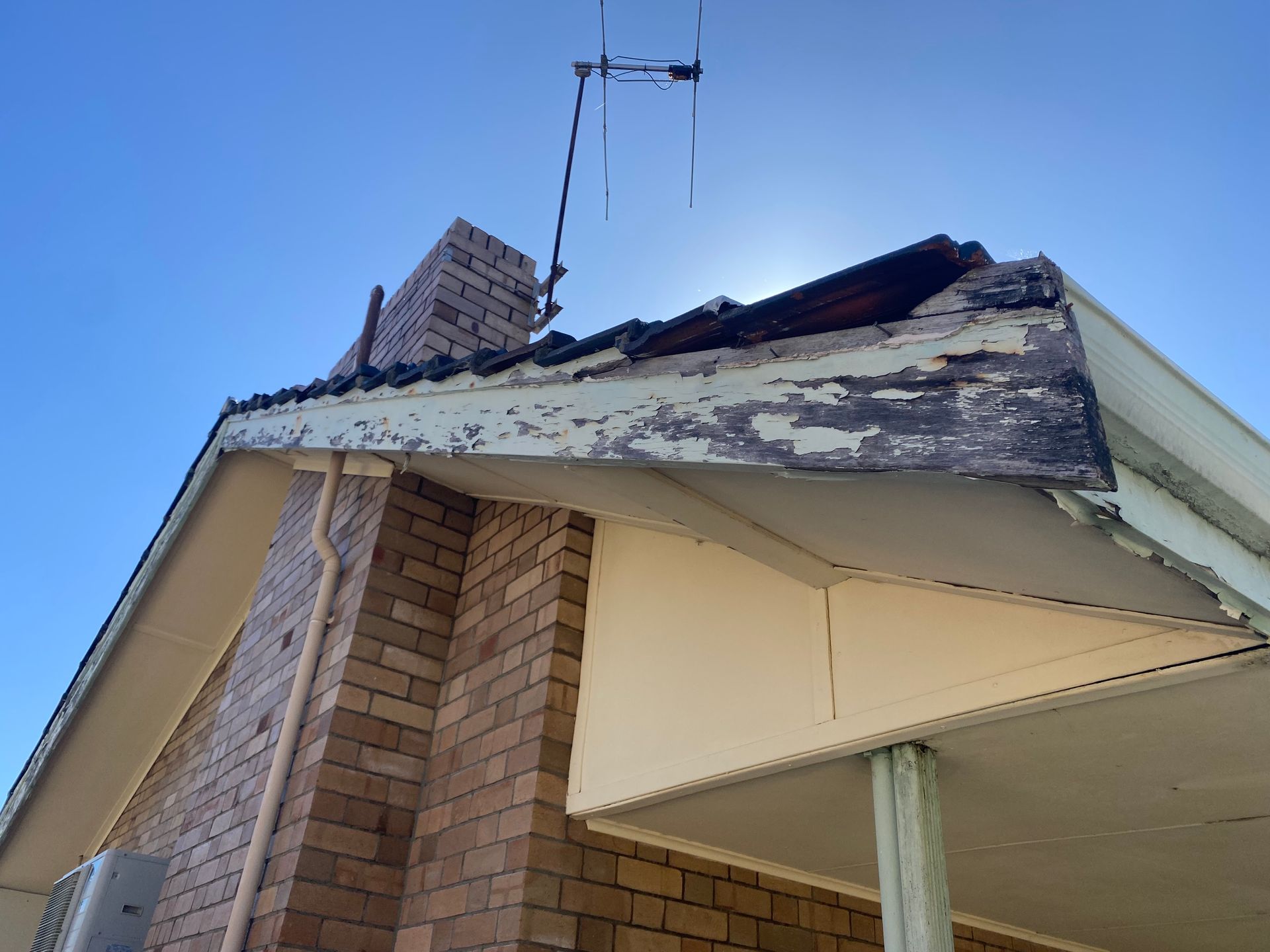 A brick house with a roof that has a chimney on it.