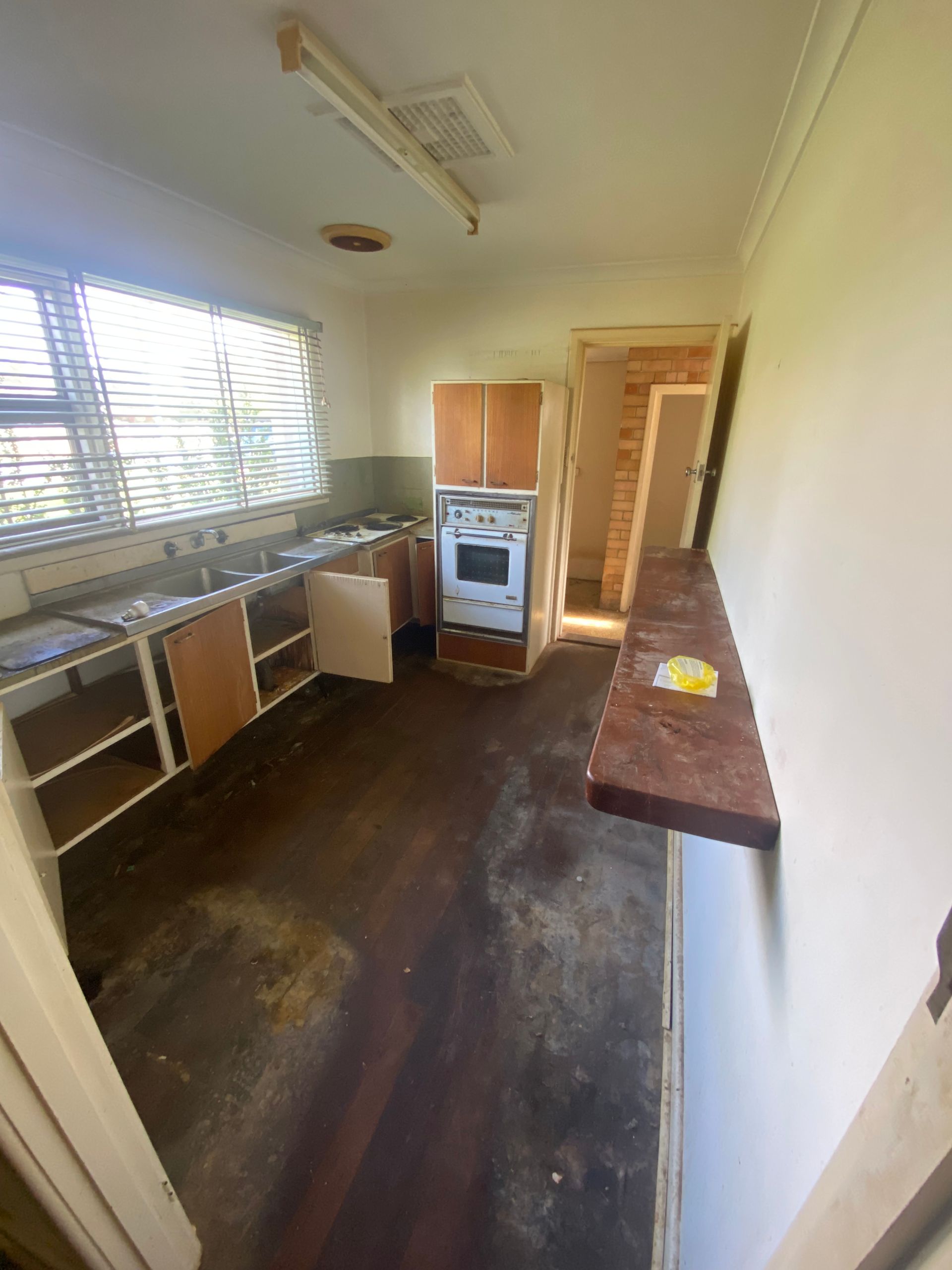 An empty kitchen with wooden cabinets and a stove.