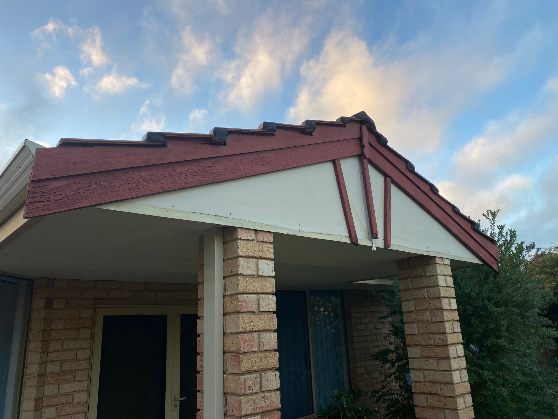 A brick house with a red roof and a porch.