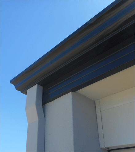 A white building with a black gutter and a blue sky in the background