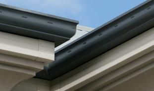 A close up of a gutter on a building with a blue sky in the background.