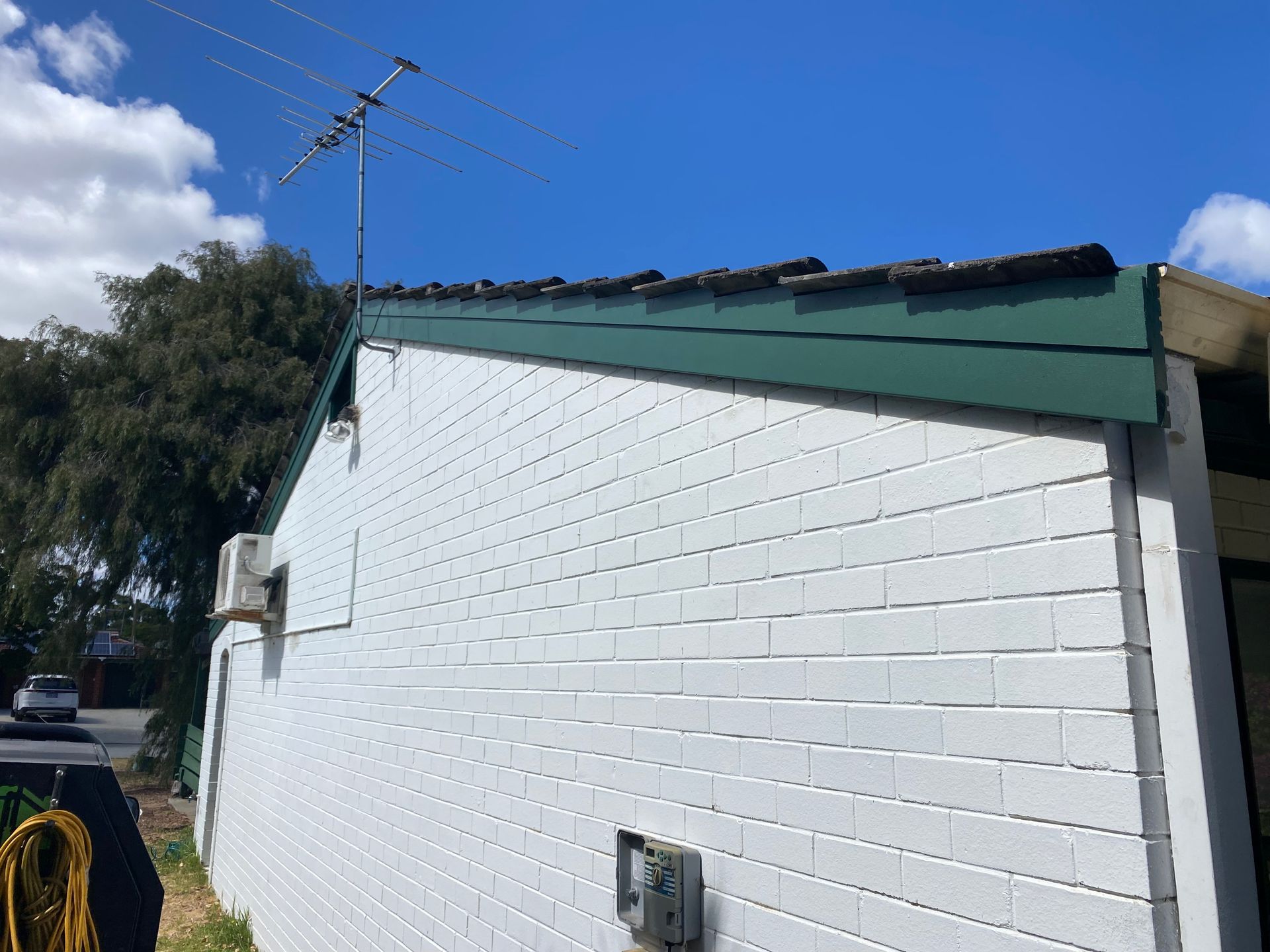 White brick building with green roof against a blue sky.