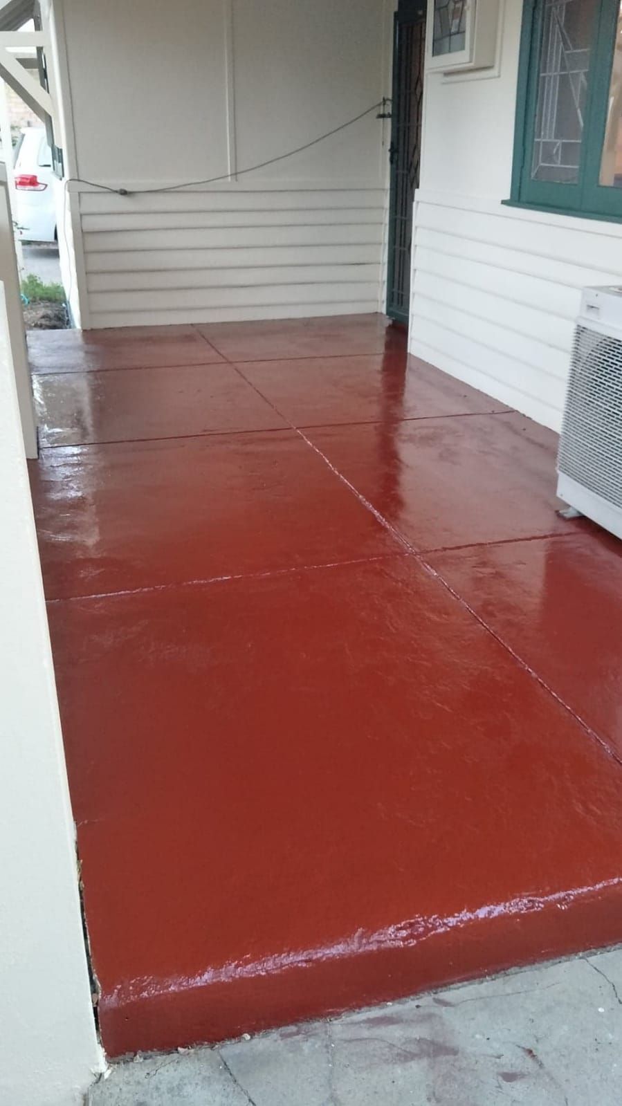 A red porch with a white wall and a window.