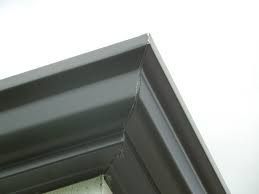 A close up of a black window frame on a white wall.