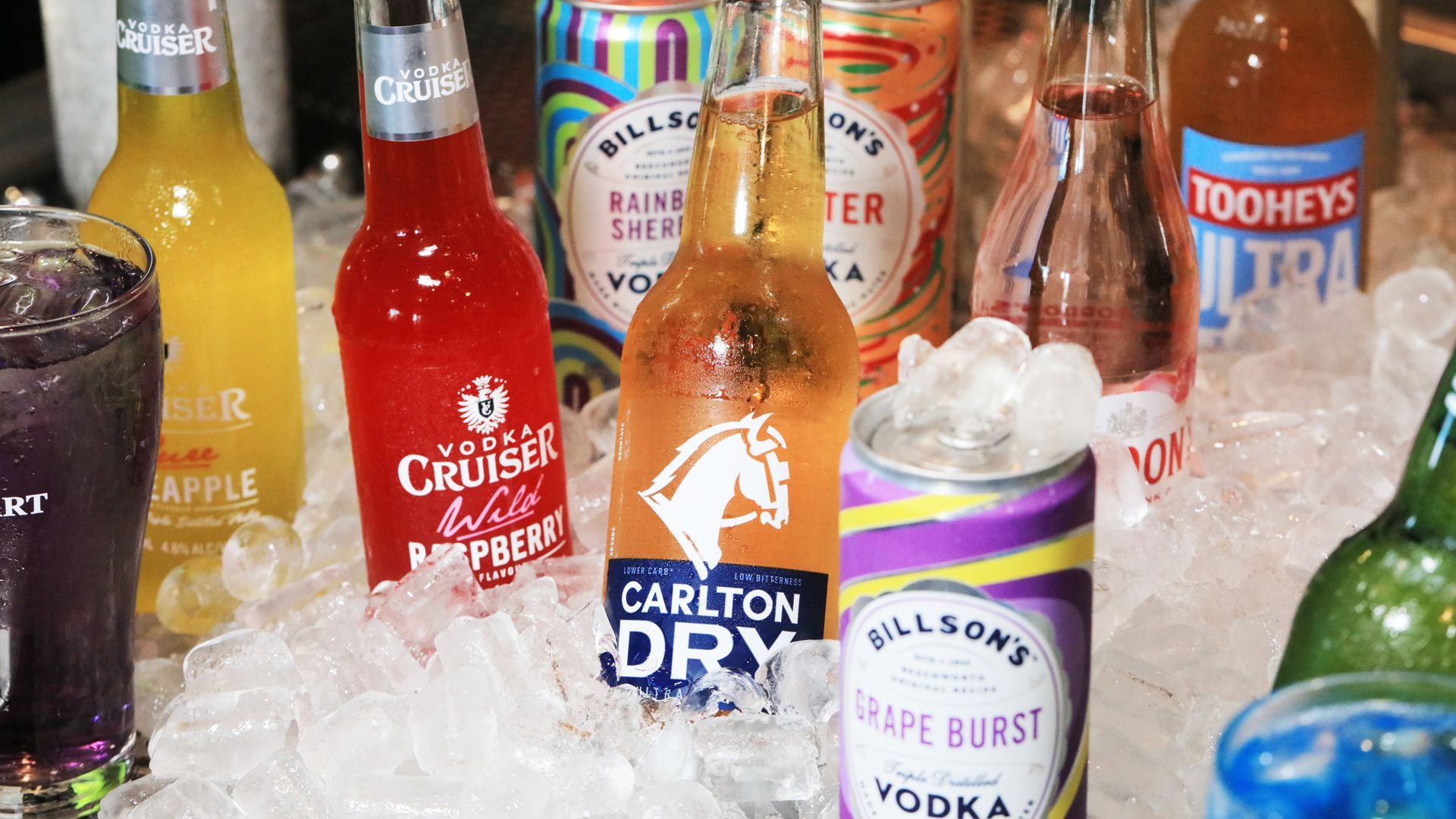 A variety of drinks are sitting on ice including carlton dry