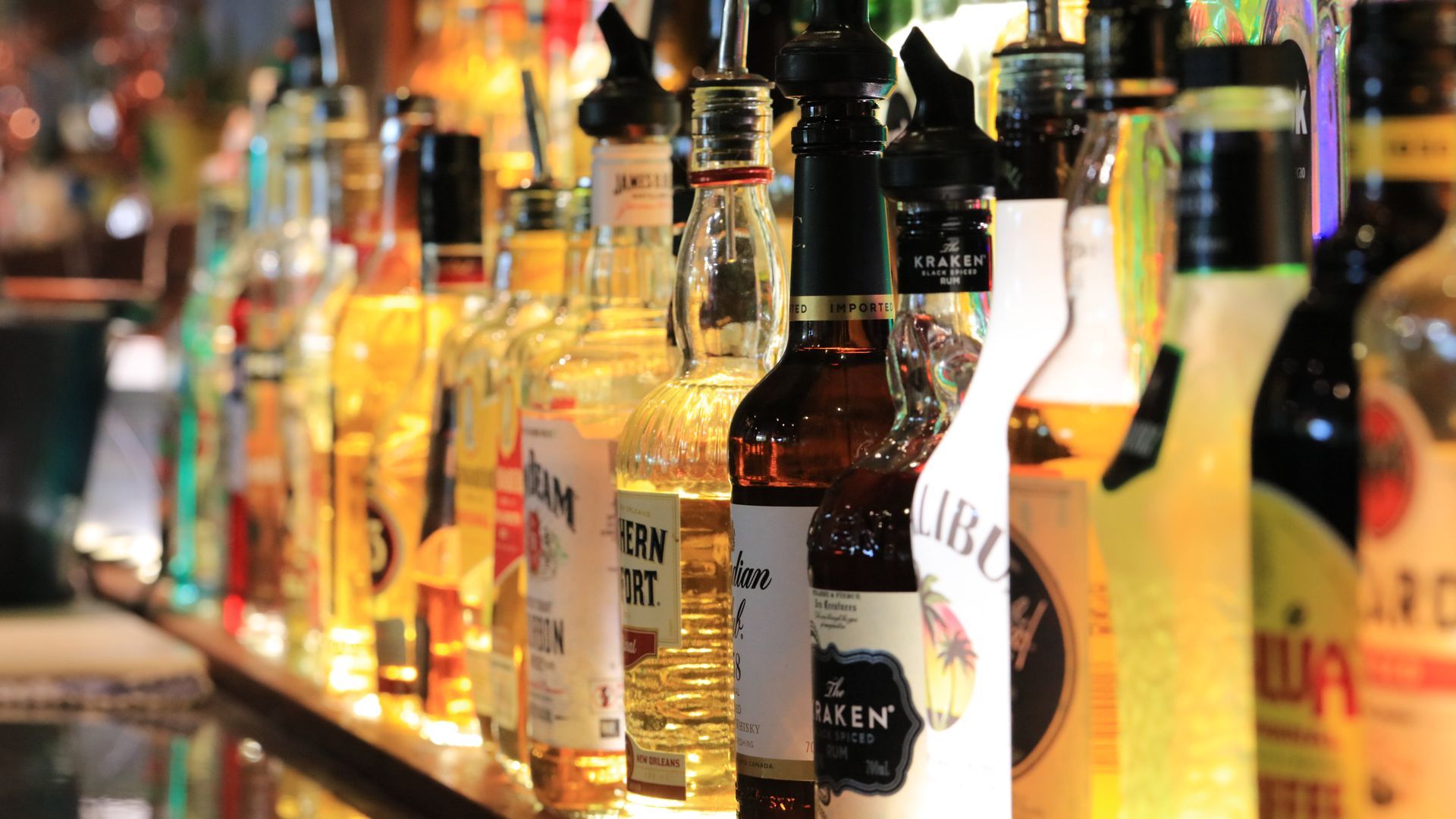 Many bottles of liquor are lined up on a bar