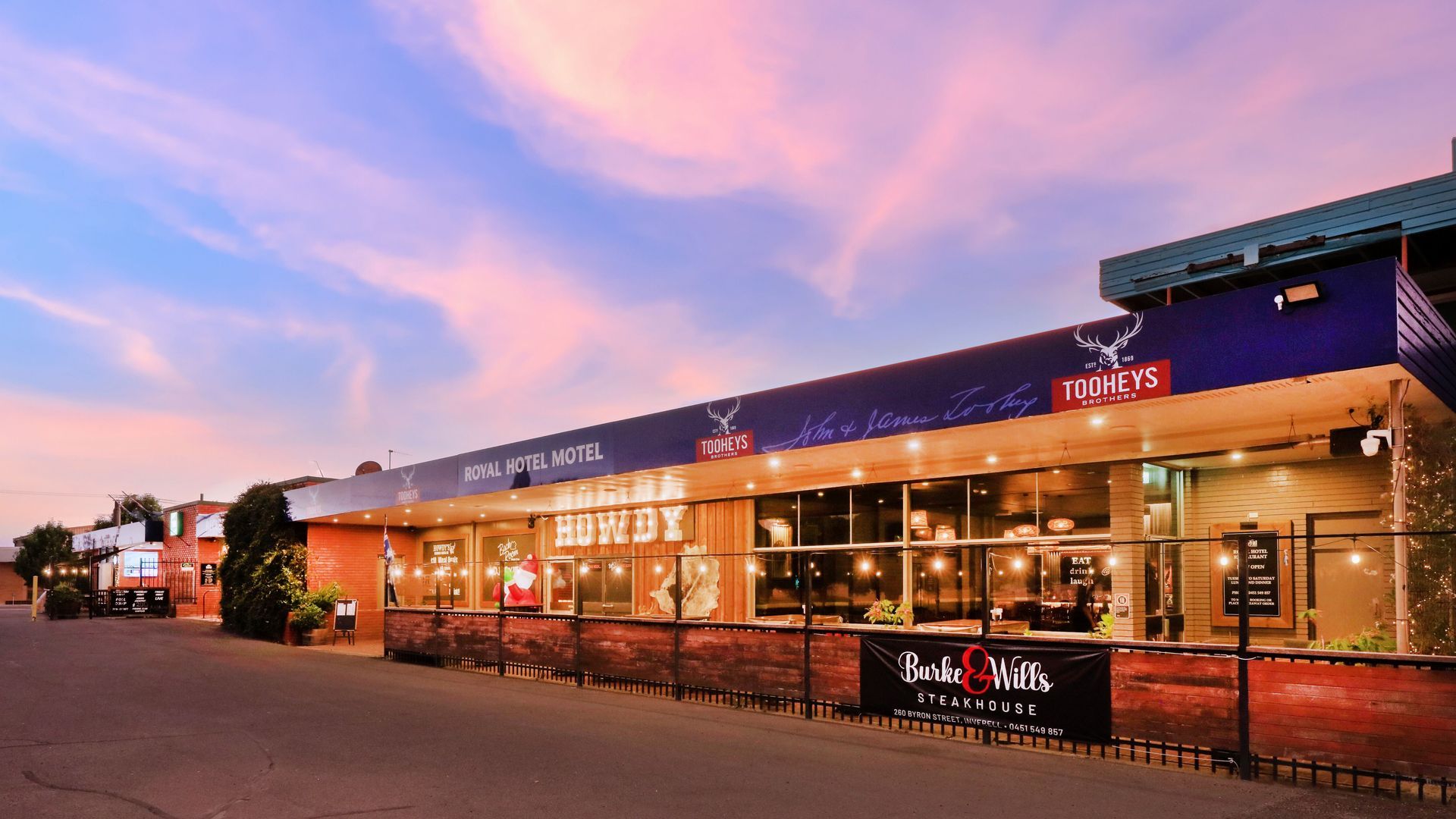 A large building with a lot of windows and a sunset in the background.