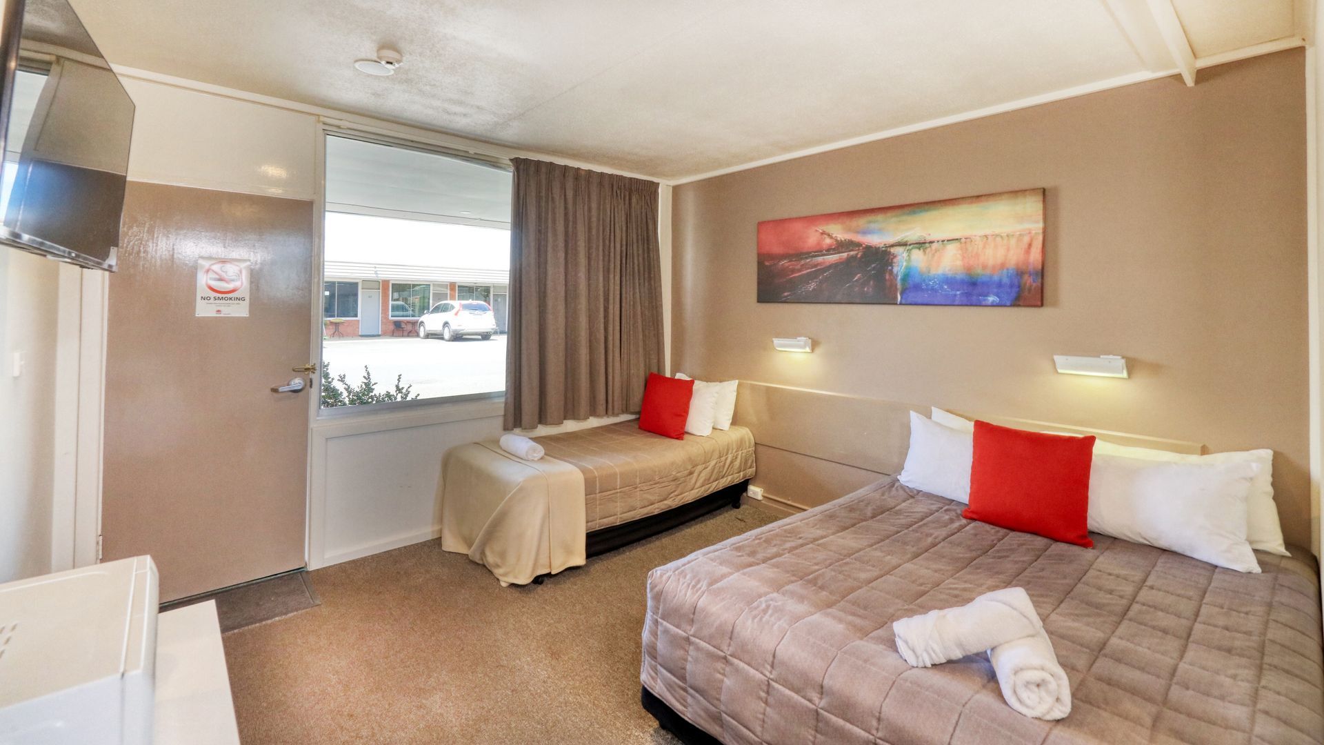 A hotel room with two beds and a television.