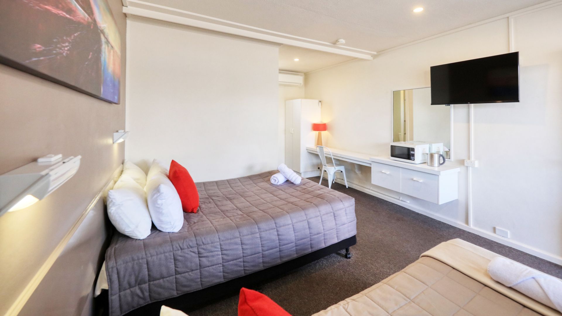 A hotel room with two beds and a flat screen tv.