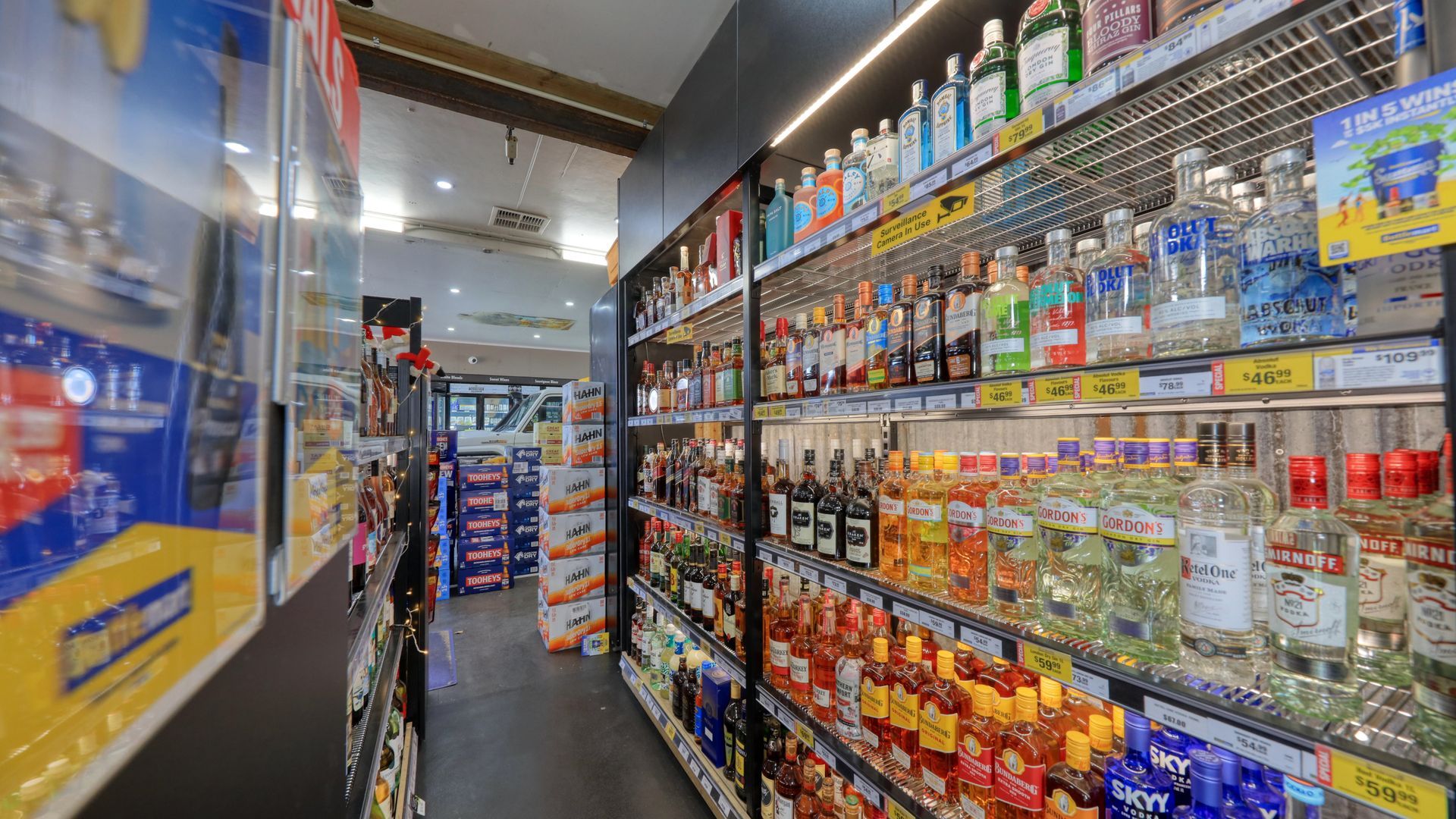 A grocery store aisle filled with lots of bottles of alcohol.