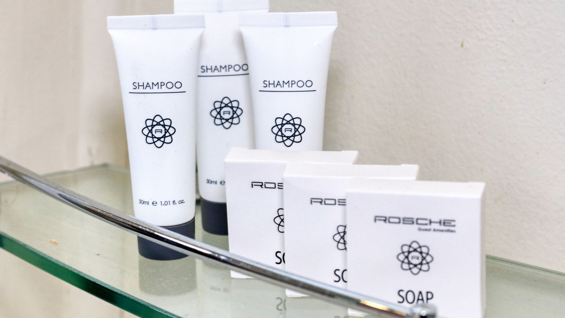 Bottles of shampoo and soap are on a glass shelf