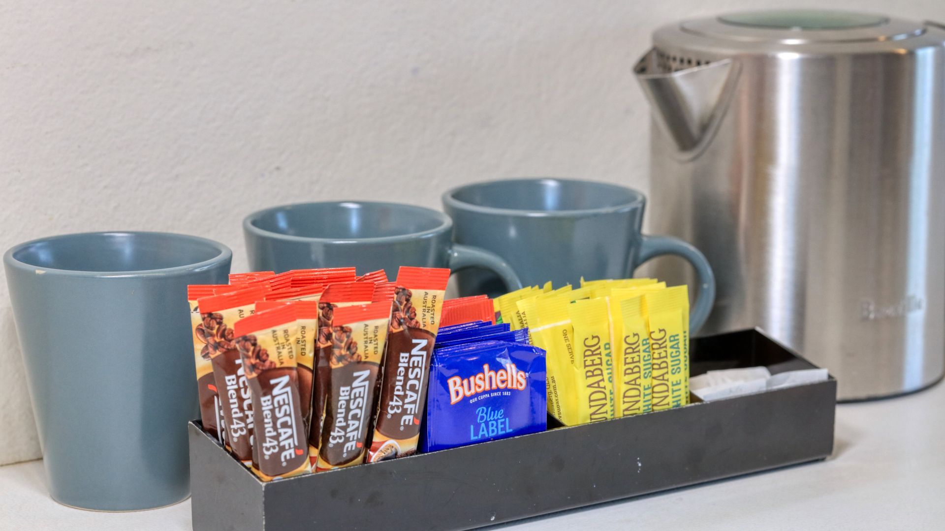 A tray of coffee and tea next to a kettle and cups.