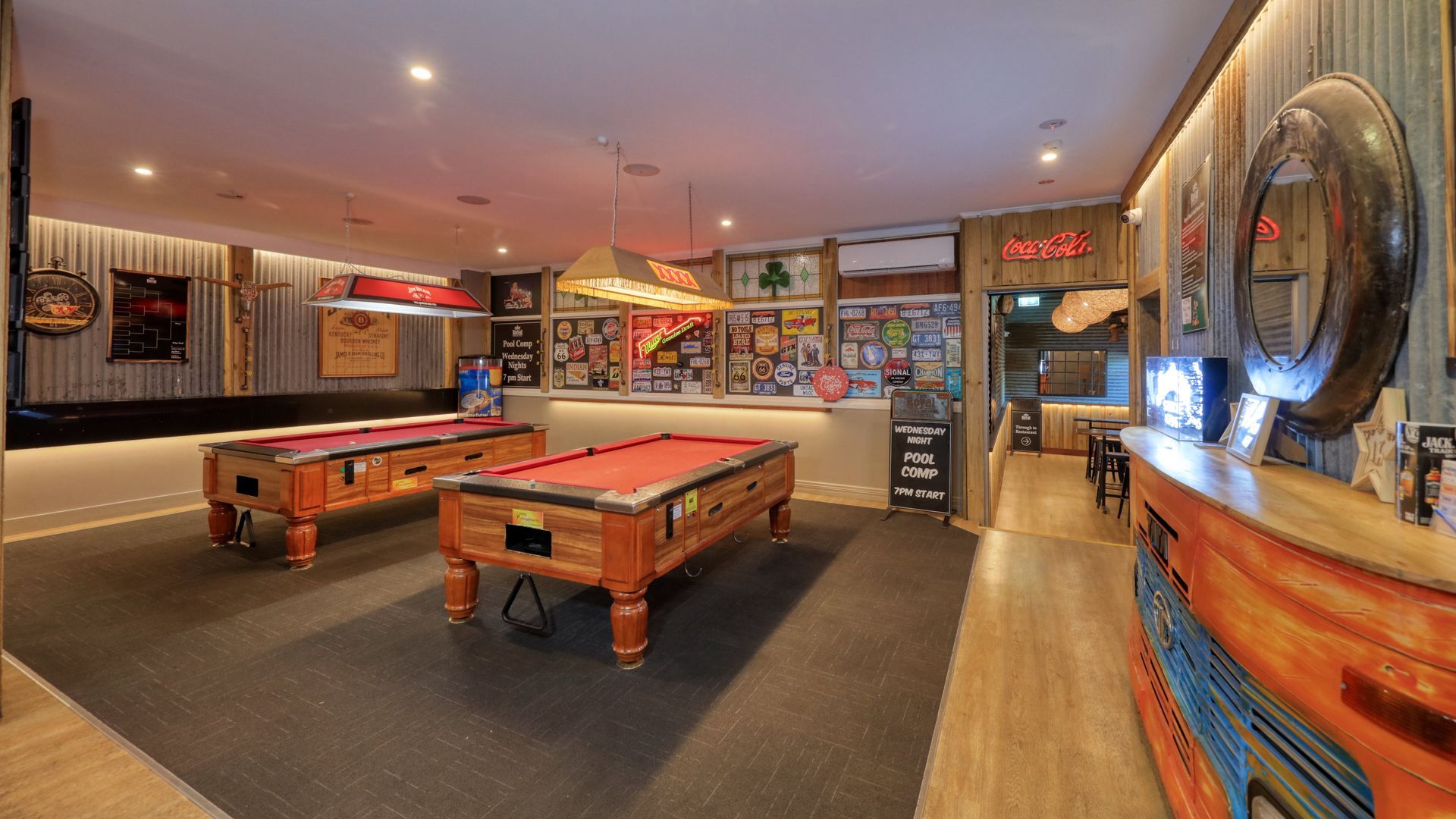 A pool hall with two pool tables and a bar.