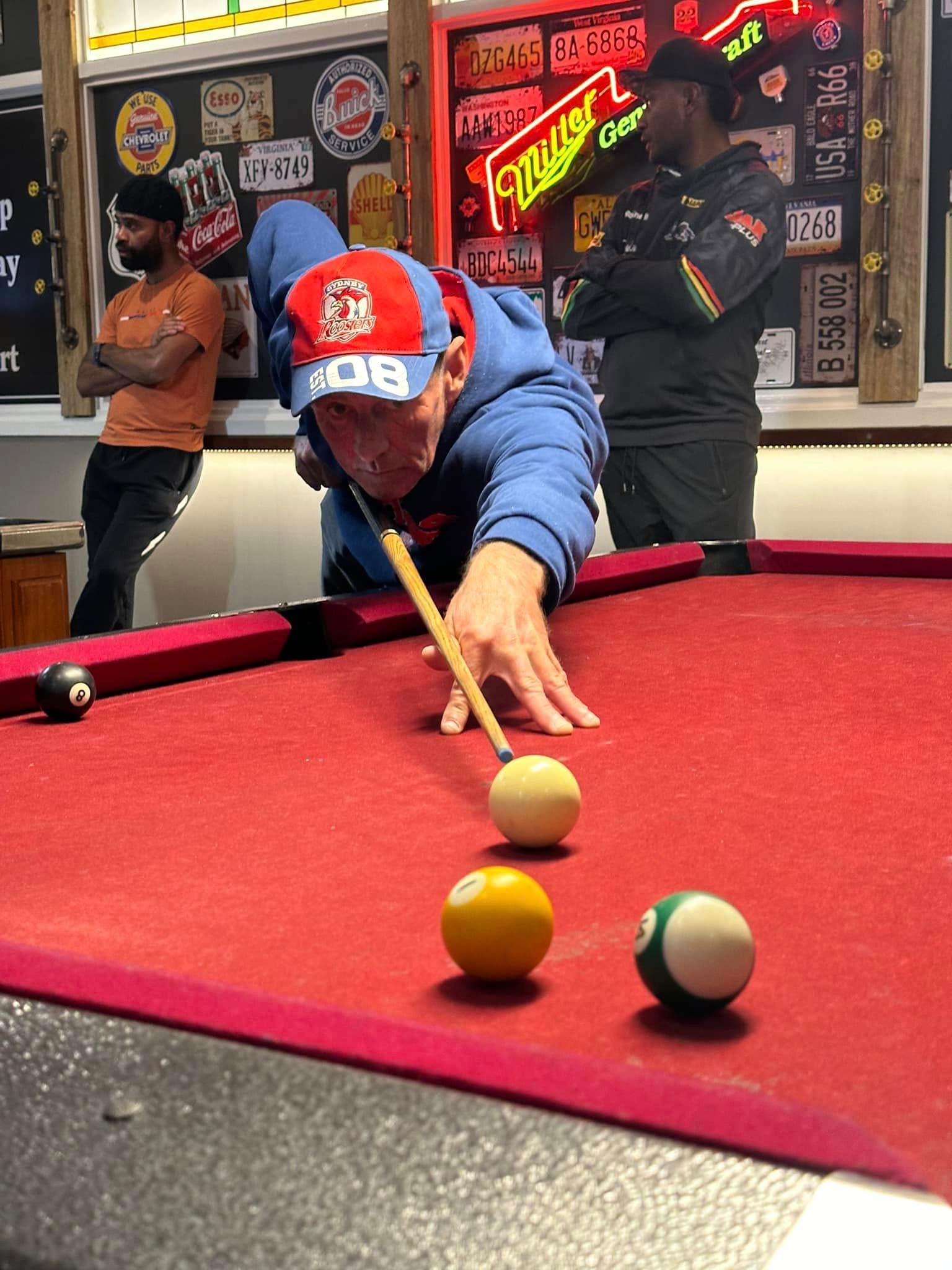 A man is playing pool in a bar with a miller lite sign in the background.