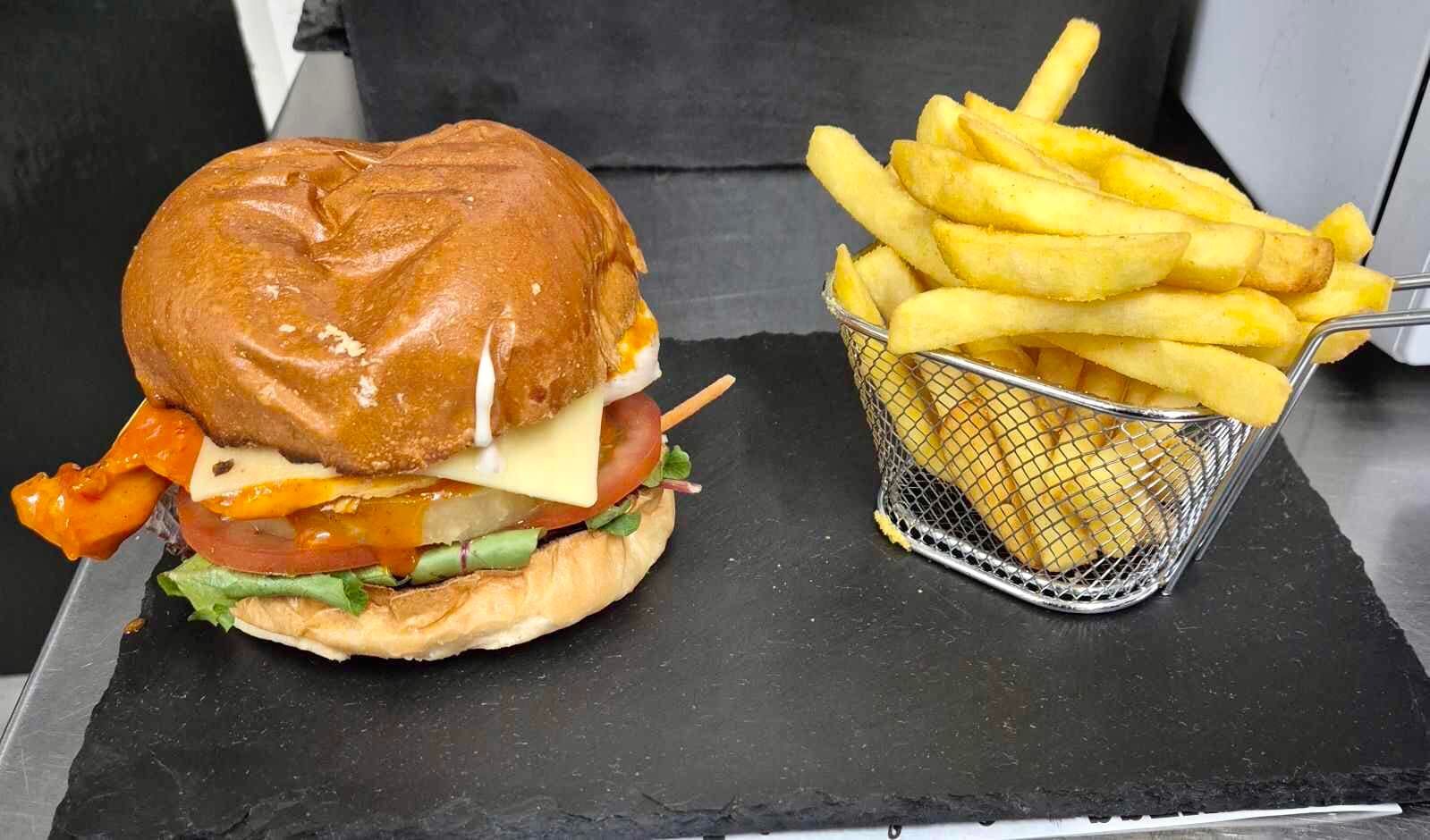 A hamburger and a basket of french fries on a table.
