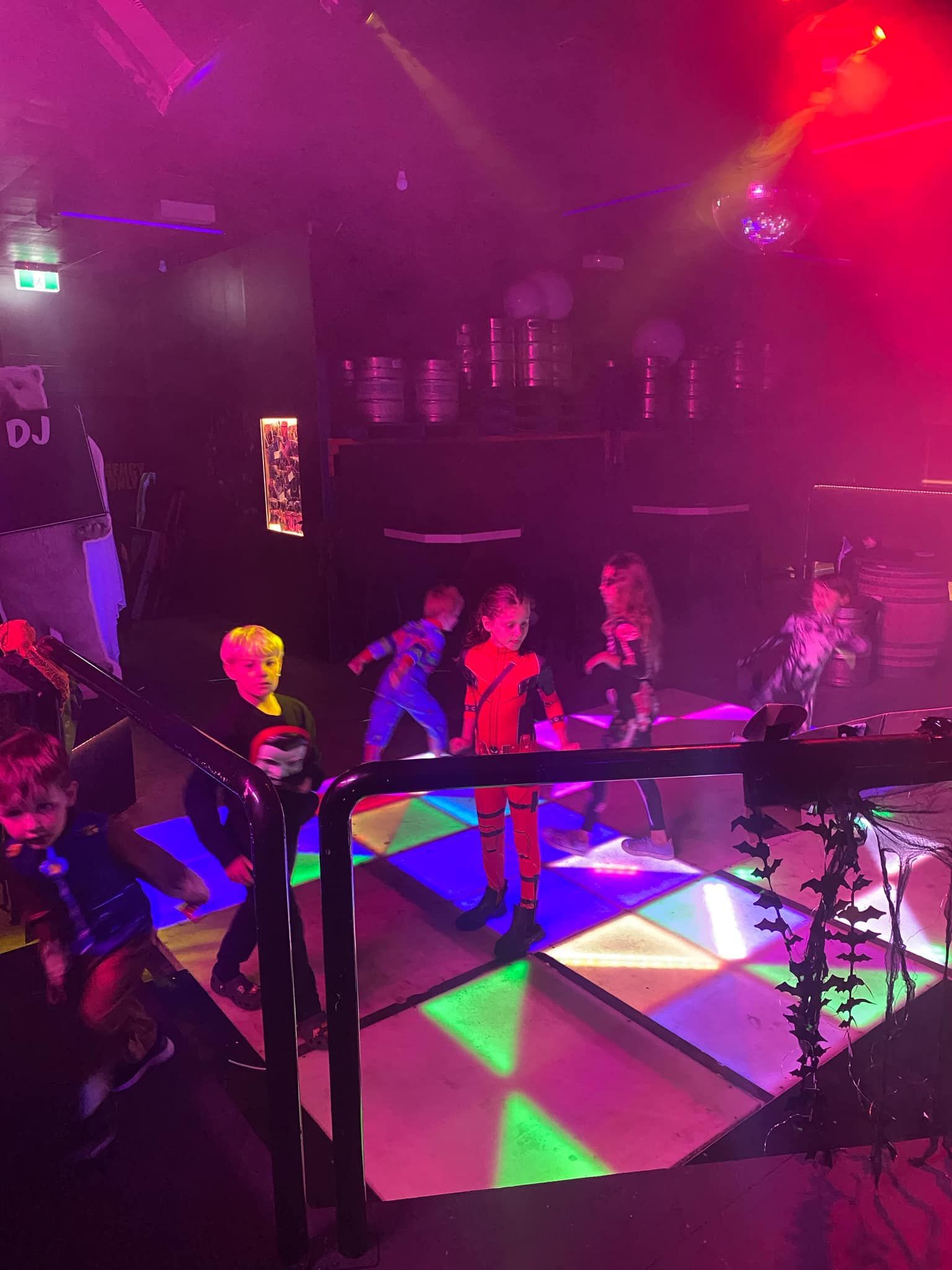 A group of children are dancing on a dance floor in a dark room.