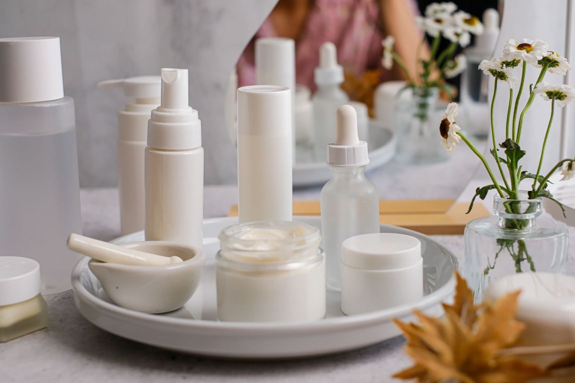 A tray of cosmetic bottles and jars on a table.