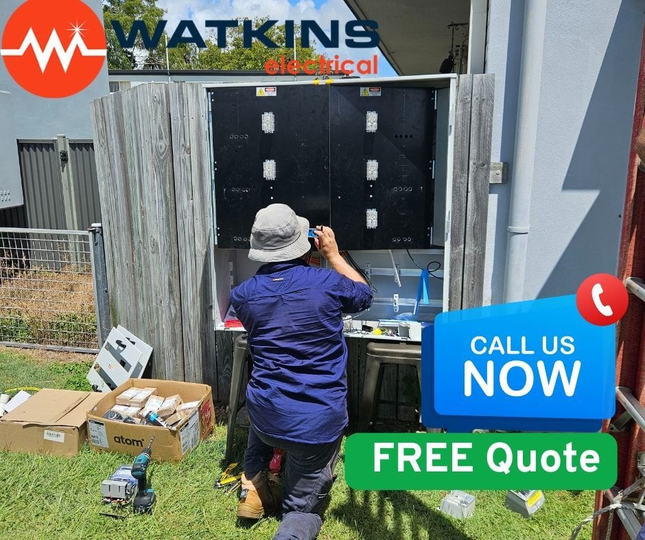 Electrician working on a switchboard outside Man beside a white truck, and white house — Watkins Electrical In Pialba, QLD