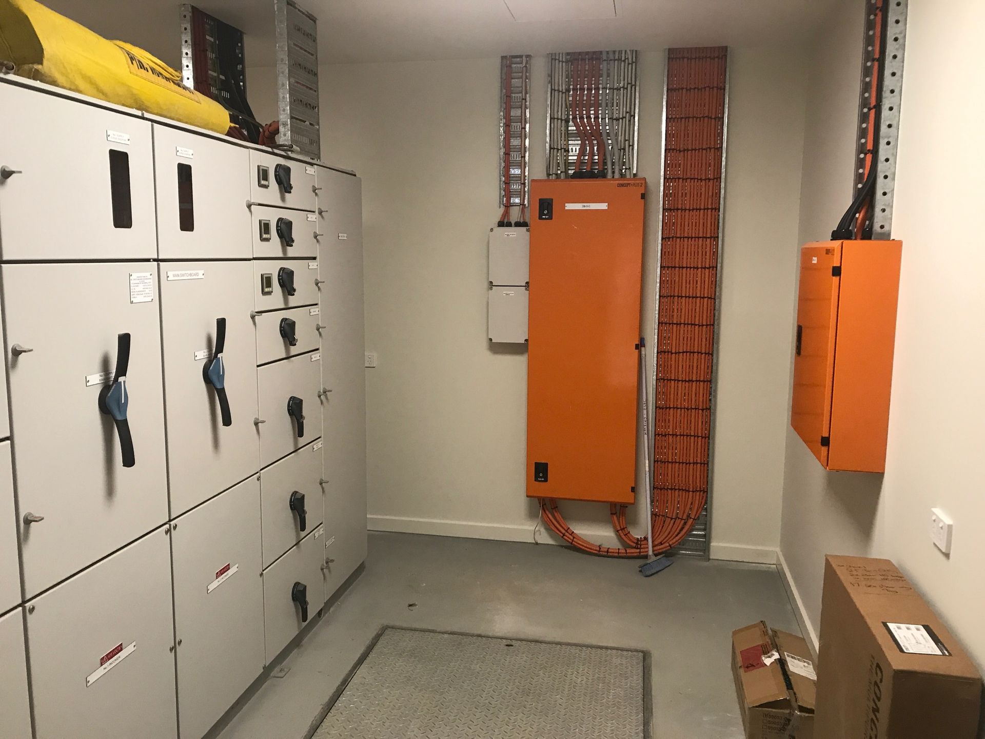 Electrical equipment room with orange and white panels, cable trays, and wiring — Watkins Electrical In Pialba, QLD